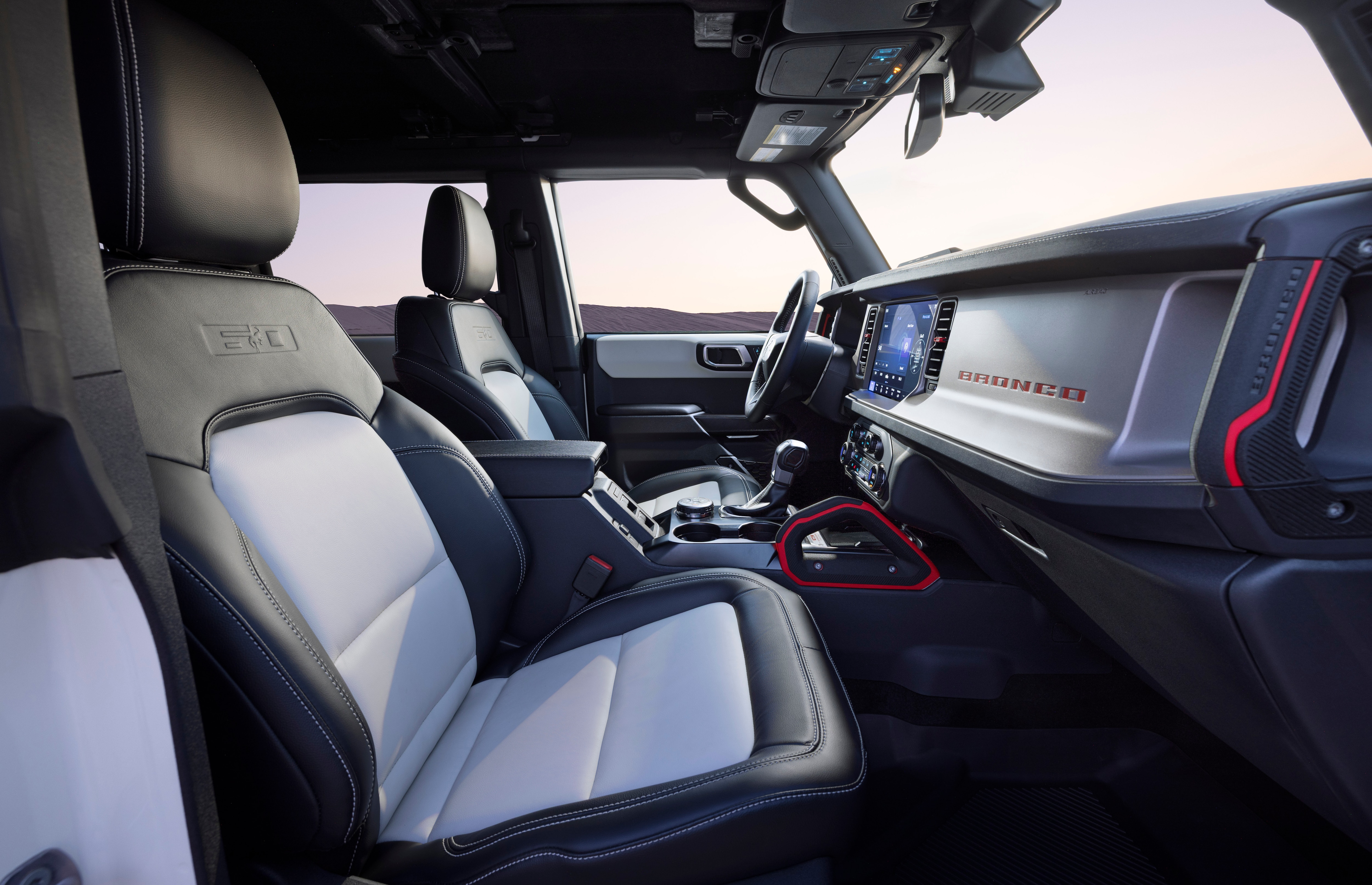 2026 Ford Bronco 60th Anniversary Package interior shown. Red accents on the dashboard complement gray and white seats.